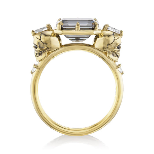 ::color_yellow ::| 2.5ctw emerald cut grey moissanite engagement ring Juliet Skull memento mori yellow gold diamond accents standing side view