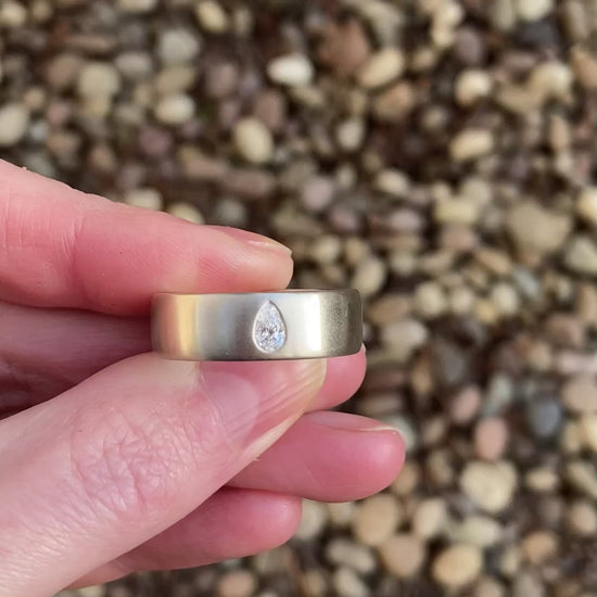 wide wedding band with pear diamond white gold video held in hand
